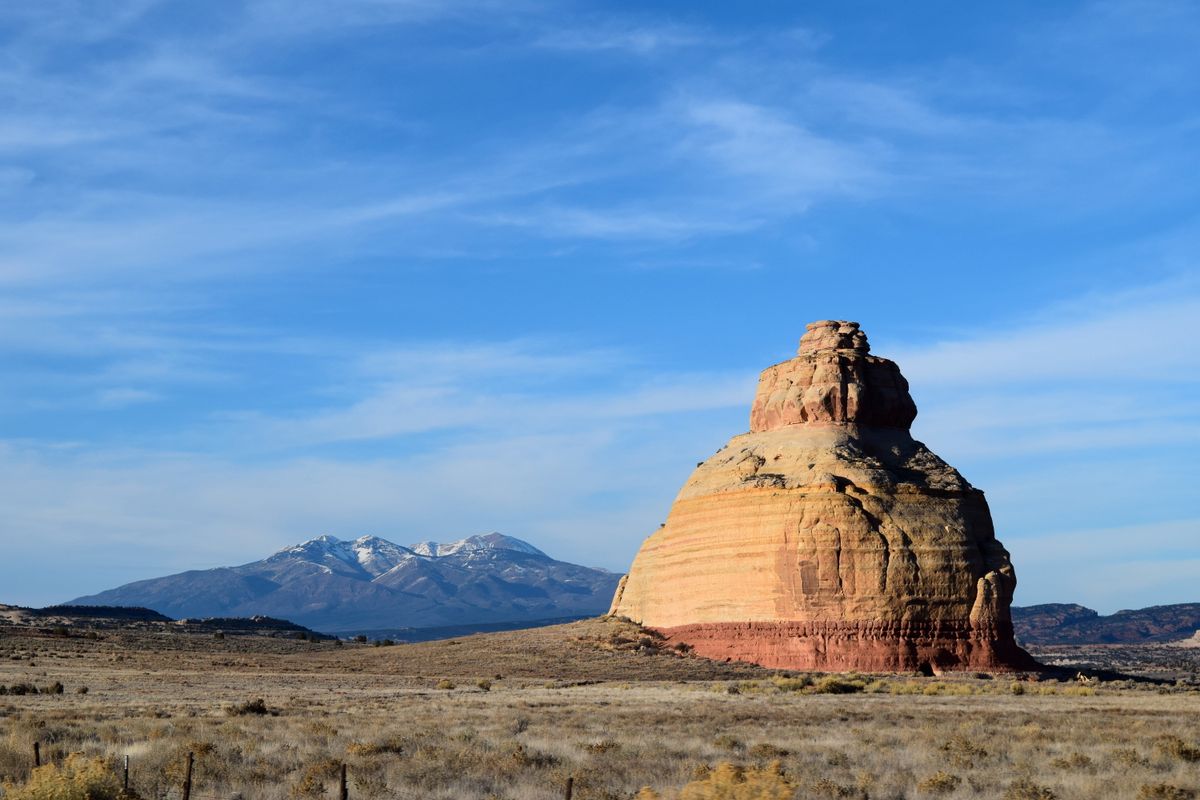 A sandstone butte standing before the snow-dusted La Sal mountains